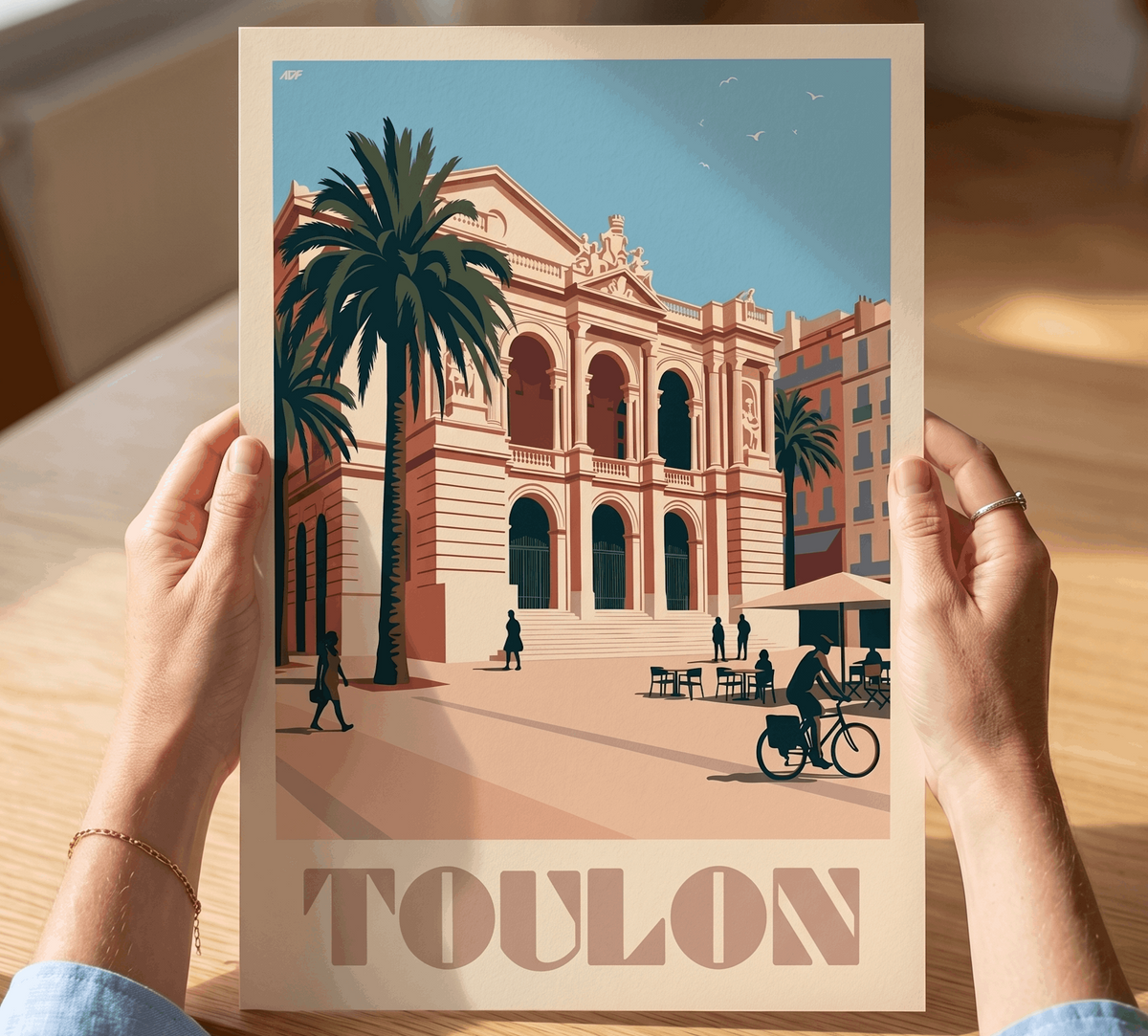Affiche vintage de Toulon tenue en main, illustrant les façades colorées du centre-ville sous les palmiers.
