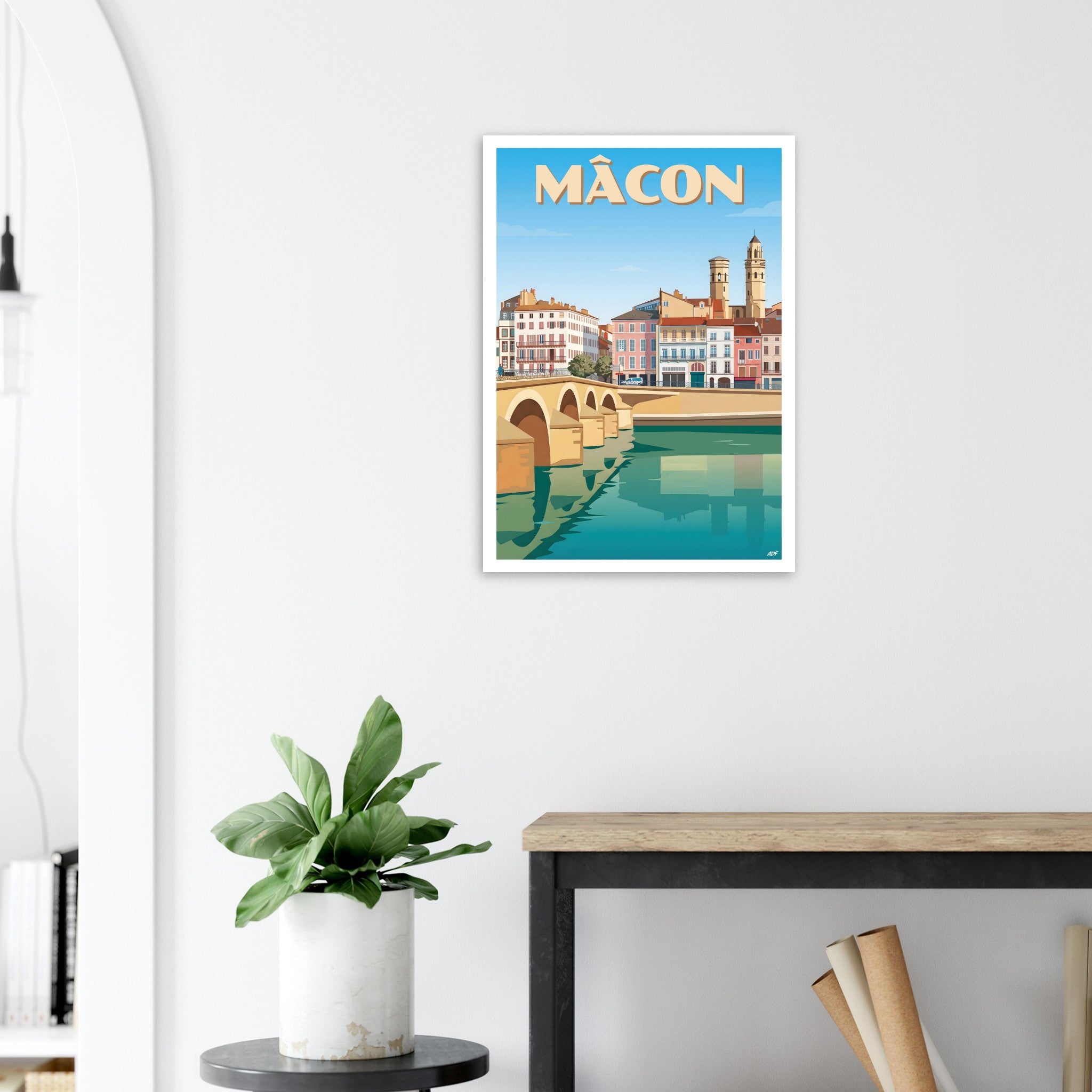Poster de Mâcon sous cadre posé sur une console en bois clair avec une plante