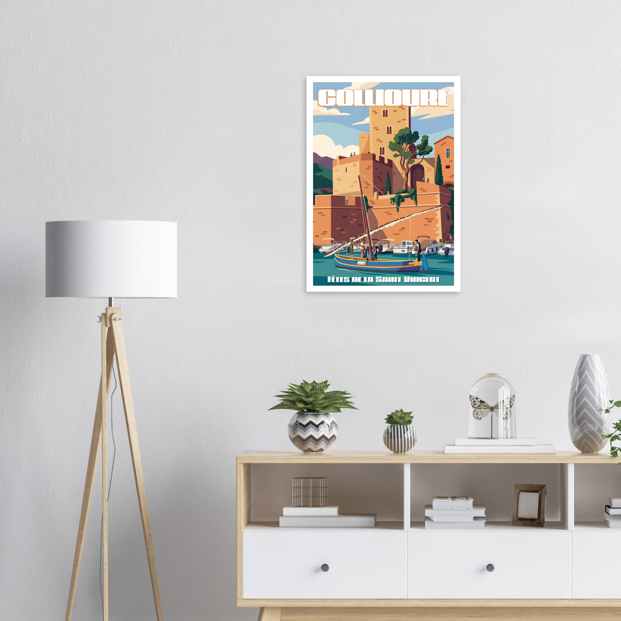 Affiche encadrée de Collioure fixée au mur au-dessus d'un meuble bas dans un intérieur épuré