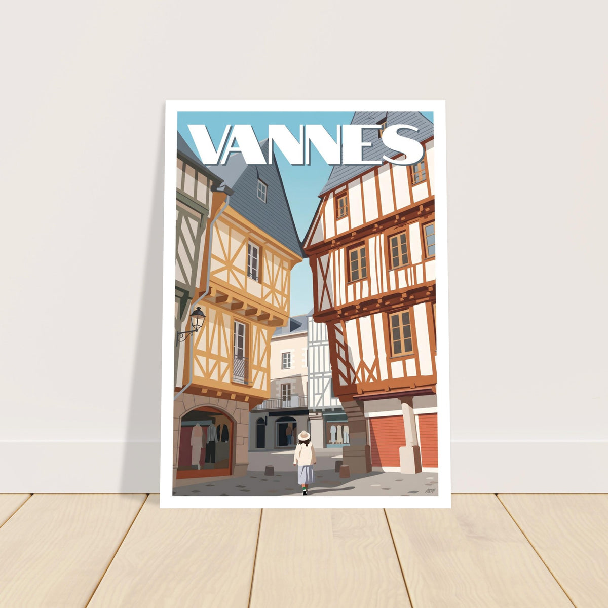 Poster du centre historique de Vannes encadré posé sur un buffet en bois clair à côté d'une lampe moderne